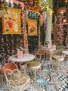 tables and chairs are set up in an ornately decorated room with flowers on the wall