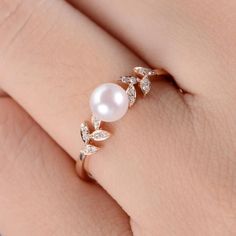 a woman's hand with a pearl and diamond ring