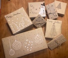 christmas presents wrapped in brown paper and decorated with hand drawn designs are sitting on a wooden table