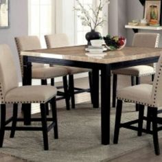 a dining room table with chairs and a rug on the floor