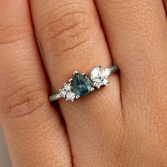 a woman's hand with a diamond and blue stone ring on her left hand