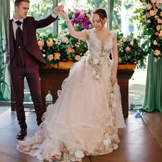 the bride and groom are dancing together in front of floral arrangements at their wedding reception