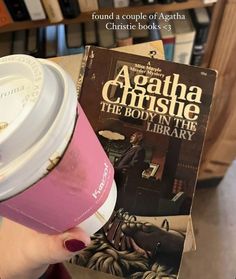 a person holding a coffee cup in front of a book