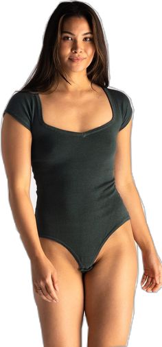 a woman in a green bodysuit posing for the camera with her hands on her hips