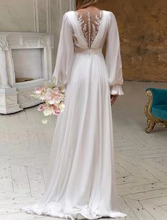 a woman in a white wedding dress standing on a tile floor with her back to the camera