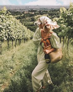 a woman carrying a wicker basket in a vineyard