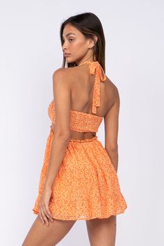 STYLE INFORMATION: Get your Texas boho vibes on in the Sundown Orange Floral Print Sundress! Orange floral print shapes this cute dress that has a halter V-neckline with tie straps, and a cutout waist. The open back wraps around the sides to create a cutout effect above the attached mini skirt. Ruffle trim and side ties decorate the cutout waist. DETAILS & CARE: Polyester. Dry Clean. Imported. SHIPPING: Orders are processed within 1-2 business days. Packages are shipped out Monday-Friday, holida Spring Halter Mini Dress For Summer Parties, Orange Backless Mini Dress For Spring, Spring Orange Backless Mini Dress, Mini Dress With Elastic Neckline For Brunch, Summer Vacation Dress With Cut-out Waist, Spring Vacation Dress With Cut-out Waist, Summer Beach Dress With Cut-out Waist, Spring Mini Dress With Elastic Neckline, Orange Halter Neck Summer Mini Dress