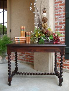 a wooden table with flowers and books on it in front of a brick wall,