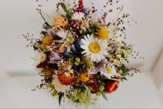 a bouquet of wildflowers and other flowers in a vase on a white surface