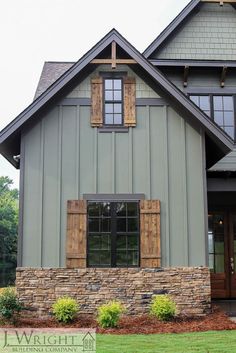 a large gray house with wooden shutters and windows