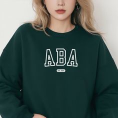 Happy graduation to all the new Applied Behavior Analysts! Congratulate a new 2024 ABA graduate with this sweatshirt! "ABA: Est. 2024" About - Classic fit unisex crewneck sweatshirt - Comfortable and cozy medium-heavy blend fabric with ribbed knit collar - Tear-away label - Fabric blends: 50% cotton and 50% polyester - Made with 100% ethically grown US cotton How to Order 1. Select your sweatshirt size from the dropdown menu. (Please review size chart in photos) 2. Select your sweatshirt color from the dropdown menu. (Colors may vary slightly due to lighting or monitor calibration) 3. Select quantity. 4. Click "Add to Cart" 5. Please click "Proceed to Check Out" That's it! Your order will be processed, printed, and ready to ship within 5 days. Shipping Standard Shipping: 3 - 8 business day Long Sleeve Tops With Letter Embroidery For Campus, Varsity Style Campus Top With Letter Embroidery, Green College Top With Letter Embroidery, Green Letter Embroidery Top For College, Behavior Analyst, Happy Graduation, Graduation Shirts, Knit Collar, New Job