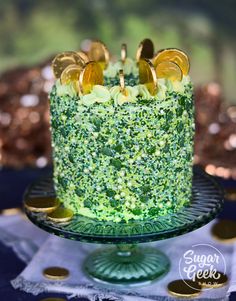 there is a green cake with gold decorations on the top and bottom, sitting on a glass platter