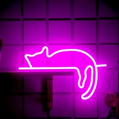 a purple neon sign with a cat sleeping on it's back in front of a tiled wall