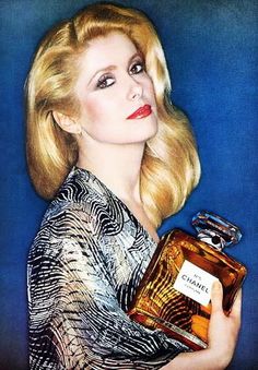 a woman holding a bottle of chanel perfume