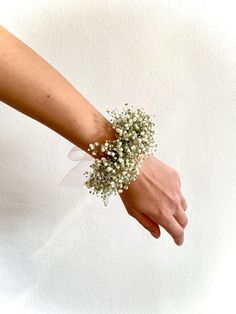 a woman's hand holding a bouquet of baby's breath on her wrist