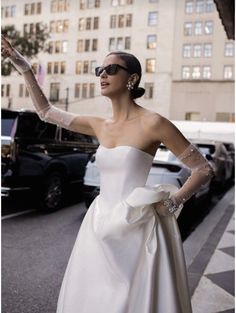 a woman in a white dress and gloves on the street