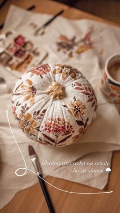 a white pumpkin sitting on top of a wooden table next to a cup of coffee