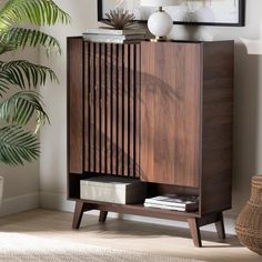 a wooden cabinet sitting next to a potted plant in a living room on top of a hard wood floor