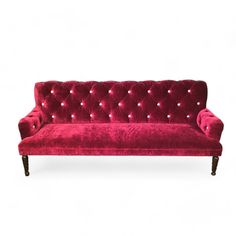 a red velvet couch with buttons on the armrests and nail polishing at the back