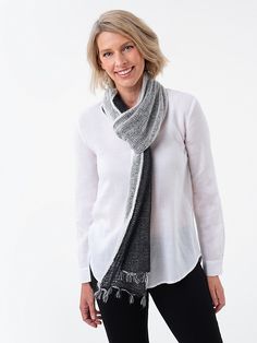 a woman wearing a white shirt and black pants with a gray scarf around her neck