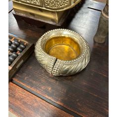 an ornate brass bowl sitting on top of a wooden table