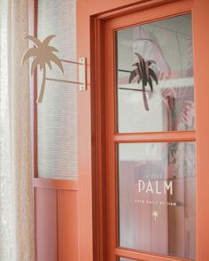 an orange door with palm trees painted on the side and window sill above it