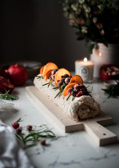 an assortment of fruits and vegetables are arranged on a cutting board with candles in the background