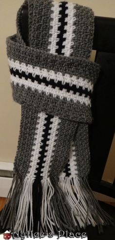 a crocheted scarf with black and white stripes on the ends is sitting on a chair