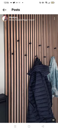 a coat hanging up against a wall next to a black cabinet with two coats on it