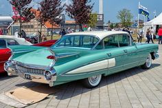 an old car is parked on the side of the road in front of other cars