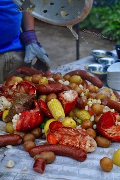 lobsters, corn on the cob, and potatoes are piled up on a table