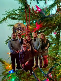 a group of people are hanging on a christmas tree