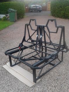 a metal structure sitting on top of gravel next to a parking lot with a car in the background