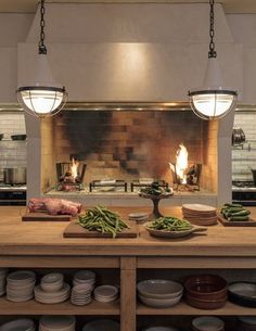 a large kitchen with many plates and bowls on the counter, along with lights hanging from the ceiling