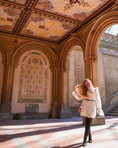 a woman standing in an ornate building with her hair blowing in the wind and wearing black boots