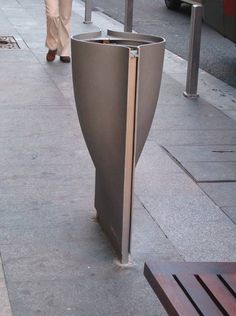 a person walking down a sidewalk next to a tall metal object