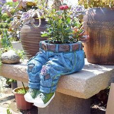 a pair of blue jean pants sitting on top of a stone bench next to potted plants