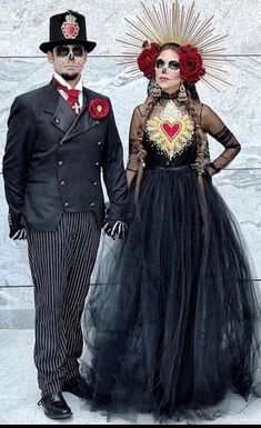 a man and woman dressed up in costume for the day of the dead, standing next to each other