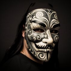 a man wearing a white mask with black and grey designs on it's face