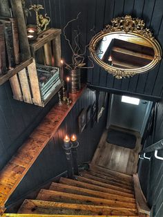 the stairs lead up to an upstairs room with candles and books on it, along with a mirror