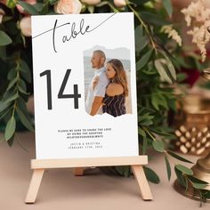 a wedding table number card on a easel with flowers and candles in the background