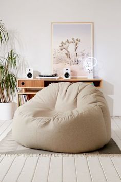 a large bean bag chair sitting on top of a wooden floor next to a potted plant