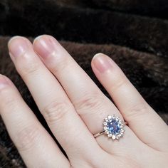 a woman's hand with a diamond and blue sapphire ring on top of her finger