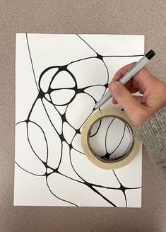 a person is using a tape to decorate a piece of paper with black and white designs on it