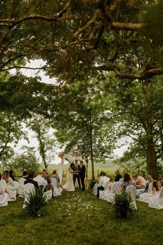 a bride and groom are standing under the trees at their outdoor wedding ceremony in an open field