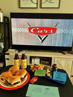 a table topped with sandwiches and condiments in front of a flat screen tv