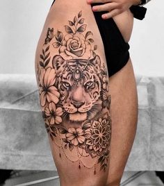 a woman's thigh with a tiger and flowers tattoo on the side of her leg