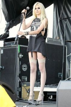 a woman standing on top of a stage with a microphone in her hand and wearing stockings