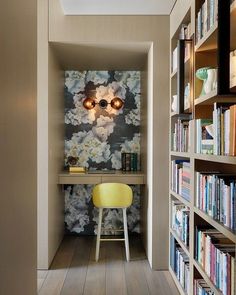 there is a yellow chair in the hallway next to bookshelves and a desk