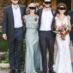 a group of people standing next to each other in front of a stone building wearing sun glasses